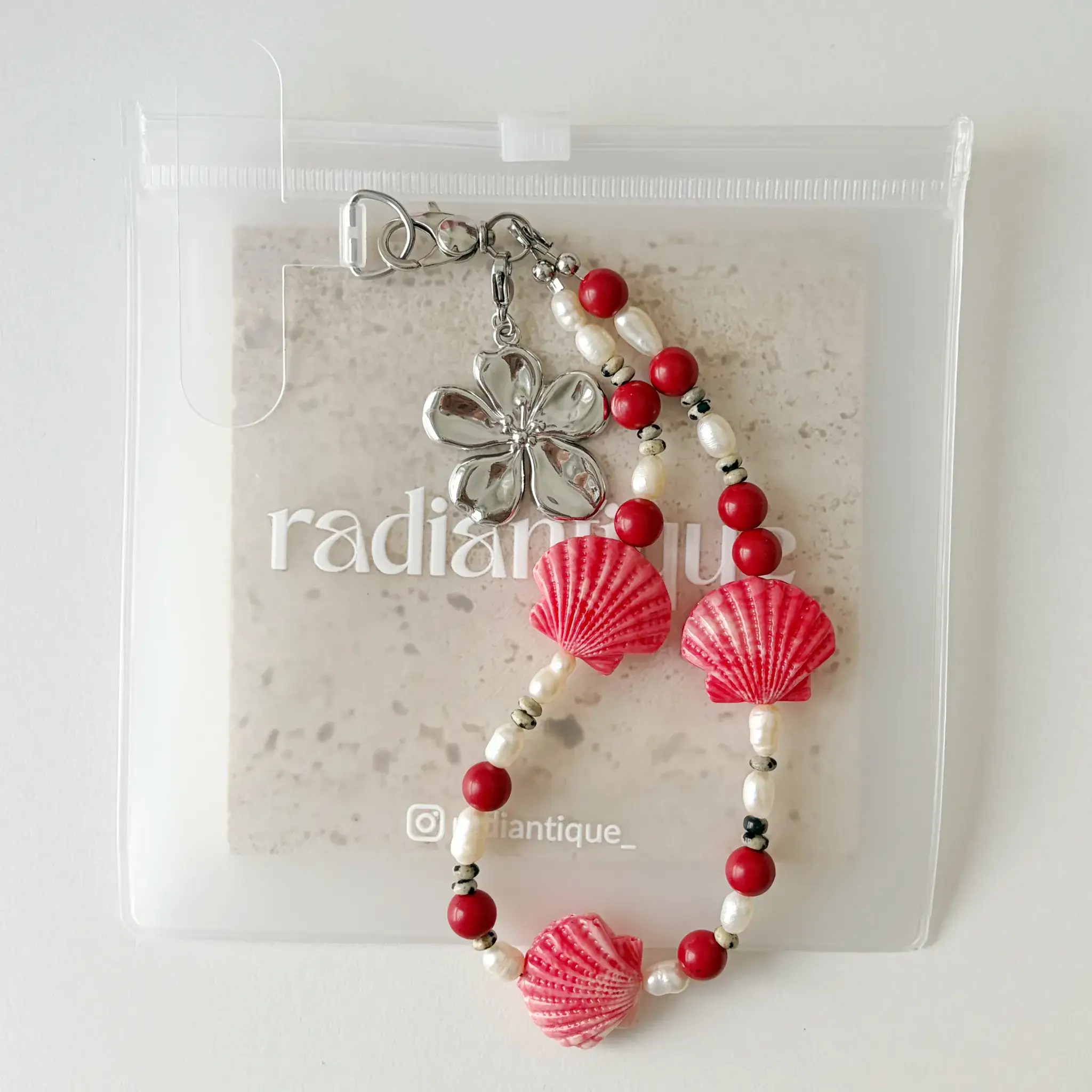 Coral Seashell phone wristlet strap in frosted packaging pouch
