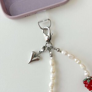 Close up of Juicy Pearl phone strap stainless steel clasp and heart pendant attached to a phone case