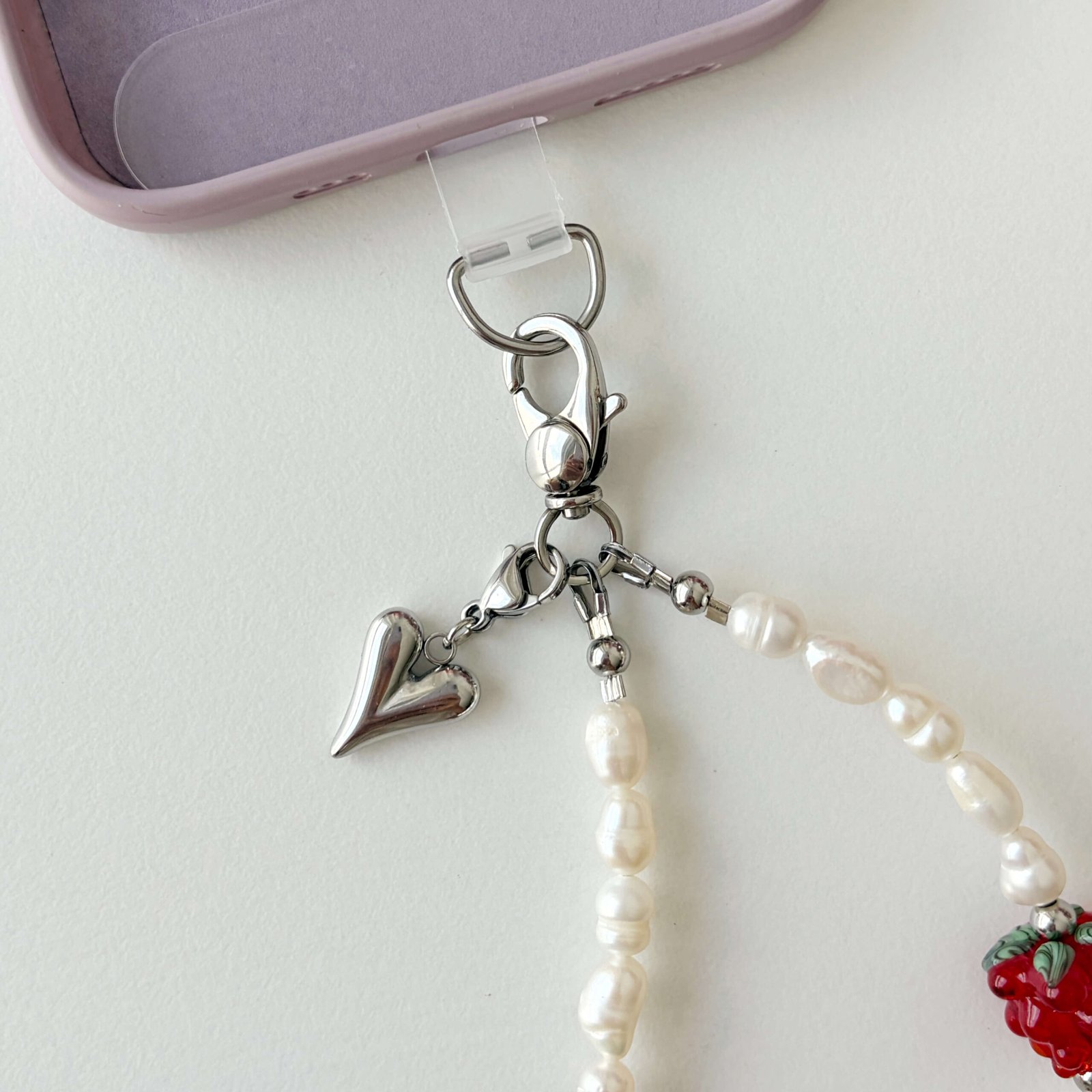 Close up of Juicy Pearl phone strap stainless steel clasp and heart pendant attached to a phone case