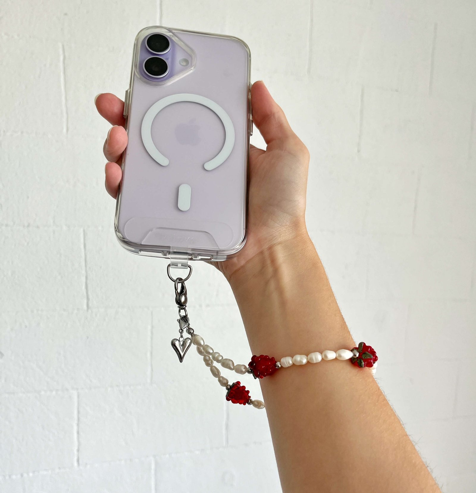 Holding phone with Juicy Pearl freshwater pearl and raspberry wristlet strap