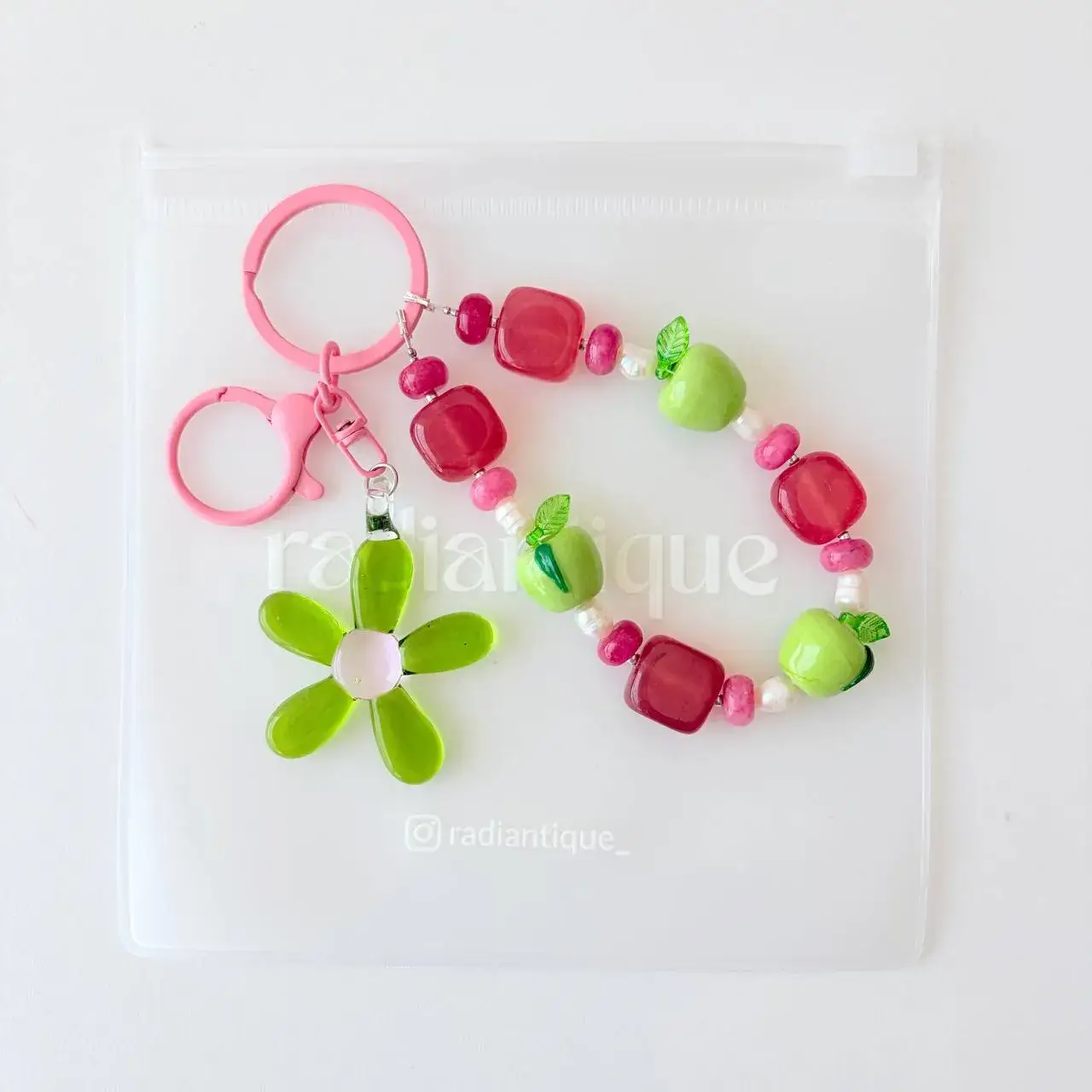 Flat lay view of Sour Apple beaded purse charm and flower pendant